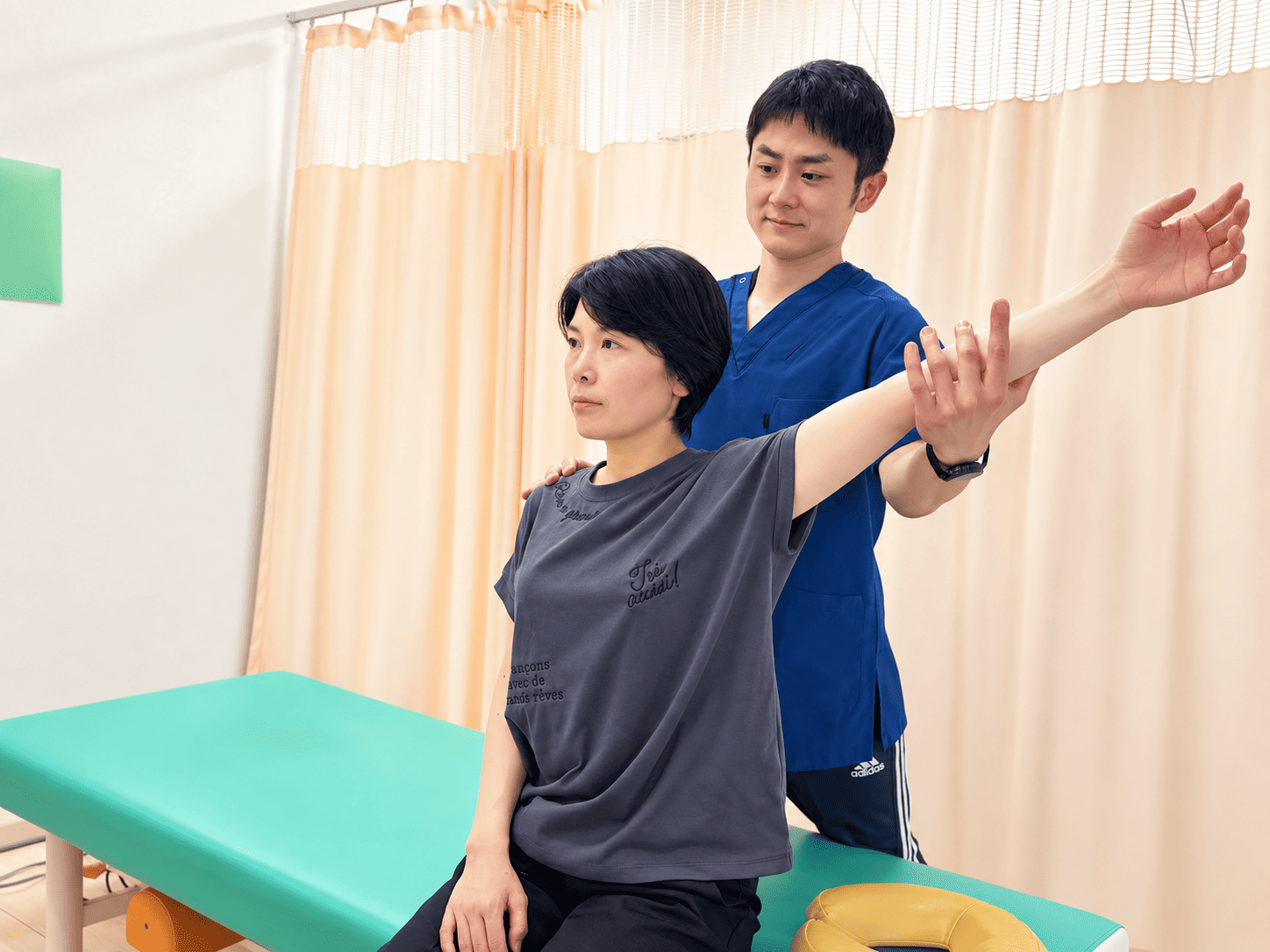 座った患者様の身体の動きを確認する施術者